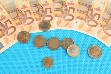 Euro banknotes and euro cents on blue background