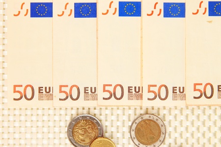 Euro banknotes and euro cents on beige background