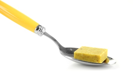 Bouillon cube on spoon, isolated on whiteの写真素材
