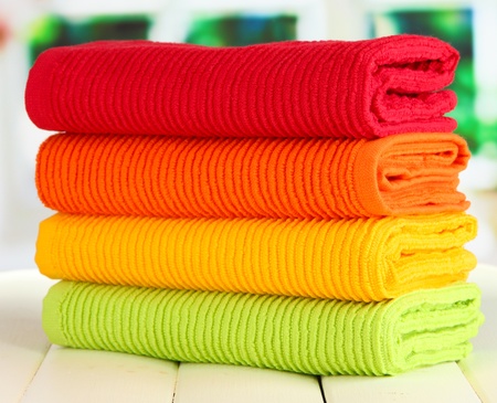 Colorful towels on wooden table on window backgroundの写真素材