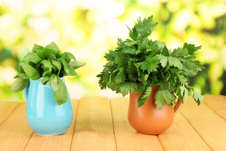 Fresh herbs in pitchers on wooden table on natural backgroundの写真素材