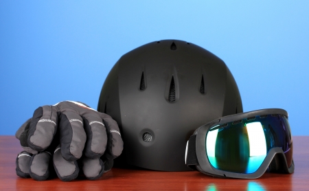 Winter sport glasses, helmet and gloves, on blue background