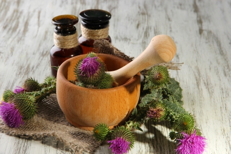 Medicine bottles and mortar with thistle flowers on wooden backgroundの写真素材