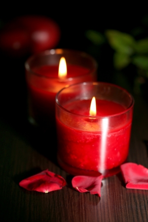 Beautiful romantic red candles with flower petals on dark wooden backgroundの写真素材