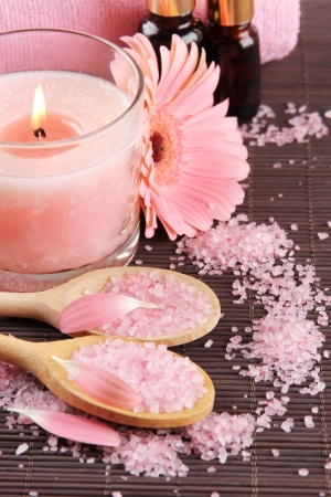 Beautiful pink candle with flower and towel on bamboo matの写真素材