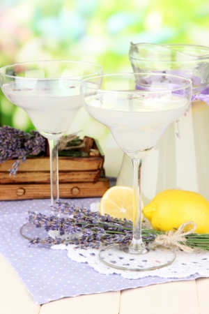 Lavender lemonade in glass jug and cocktail glasses, on bright backgroundの写真素材