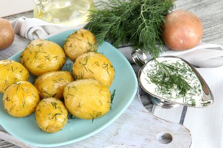 Boiled potatoes on platen on wooden board near napkin on wooden tableの写真素材