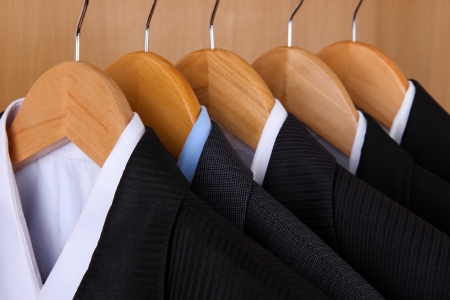 Suits with shirts on hangers on wooden backgroundの写真素材