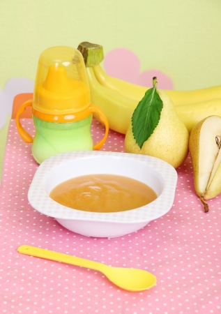Tasty baby fruit puree and baby bottle on table in roomの写真素材