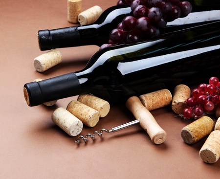 Bottles of wine, grapes and corks on brown backgroundの写真素材