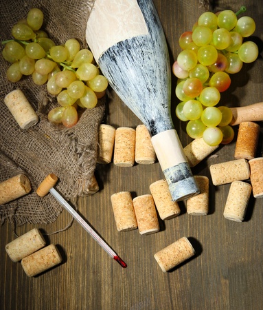 Old bottle of wine, grapes and corks on wooden backgroundの写真素材
