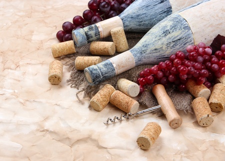 Old bottles of wine, grapes and corks on old paper backgroundの写真素材