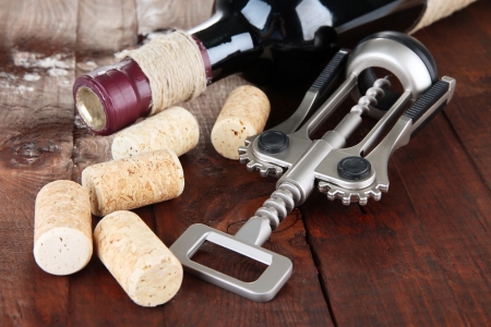 Corkscrew with wine corks and bottle of wine on wooden table close-upの写真素材