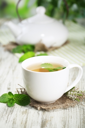 Teapot and cup of herbal tea with fresh mint on wooden tableの写真素材
