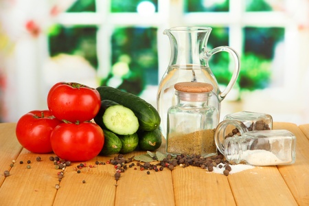 Tasty  fresh and canned cucumbers and red tomatoes, on wooden table on bright  backgroundの写真素材