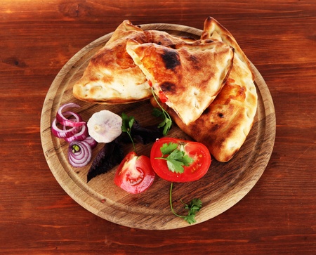 Pizza calzones on wooden board on wooden tableの写真素材