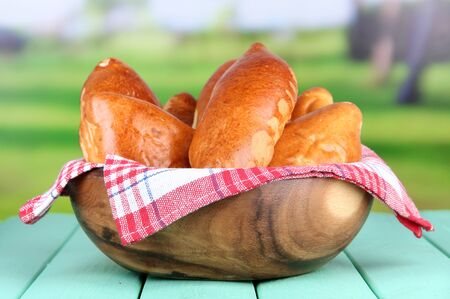 Fresh baked pasties, in wooden bowl, on wooden table, on bright backgroundの写真素材