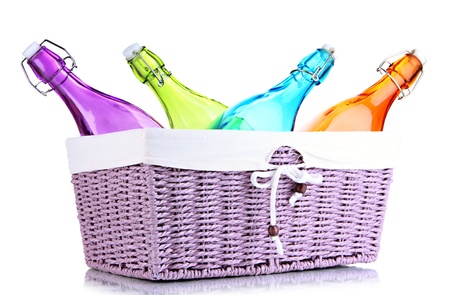 Color glass bottles in wicker basket, isolated on whiteの写真素材