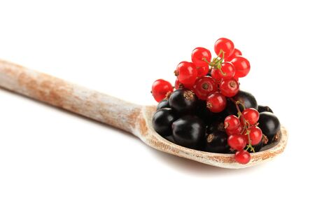 Red and black currant in wooden spoon isolated on whiteの写真素材