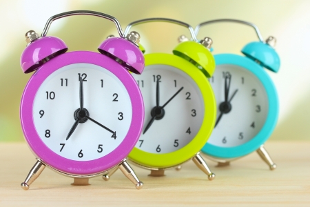 Colorful alarm clocks on table on light backgroundの写真素材