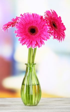 Beautiful pink gerbera flowers in vase on wooden tableの写真素材