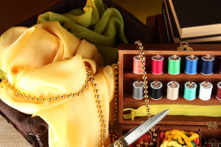 Sewing kit in wooden box with books and cloth table on bright backgroundの写真素材