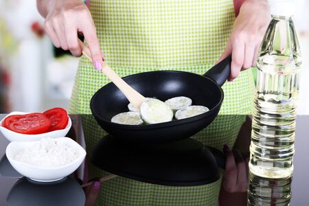 Hands cooking marrows in pan in kitchenの写真素材