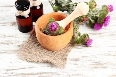 Medicine bottles and mortar with thistle flowers on wooden backgroundの写真素材