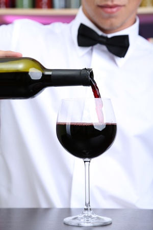 Bartender is pouring red wine into glassの写真素材