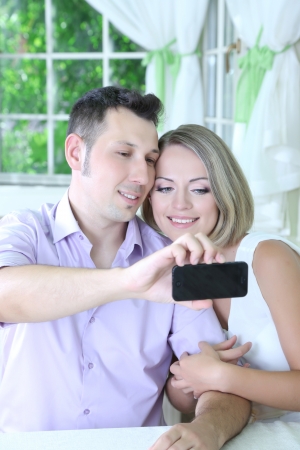Young couple  taking  photo with  mobile phone in restaurantの写真素材