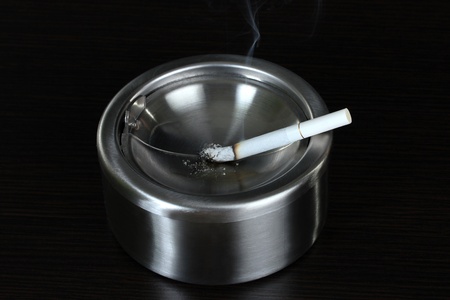 Metal  ashtray with cigarette, isolated on black