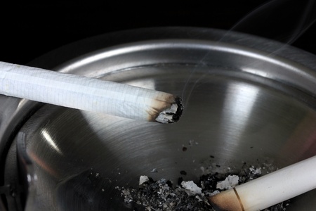 Metal  ashtray with cigarette, isolated on blackの写真素材