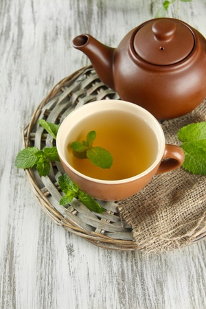 Teapot and cup of herbal tea with fresh mint on wooden tableの写真素材