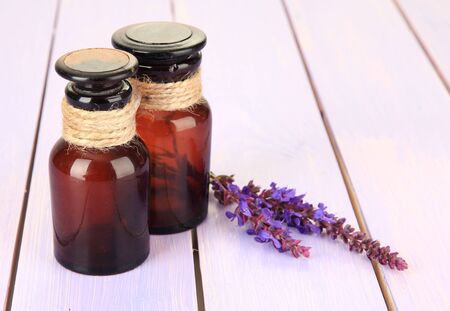 Medicine bottles and salvia flowers on purple wooden backgroundの写真素材