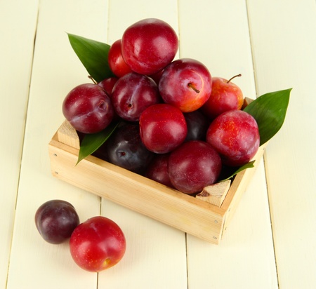 Ripe plums in wooden box on wooden table close-upの写真素材