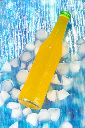 Bottle with tasty drink with ice cubes, on bright backgroundの写真素材