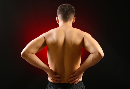 Young man with back pain, on red background