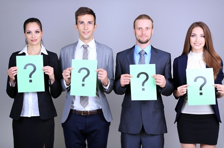 Business team standing in row with question mark on grey backgroundの写真素材