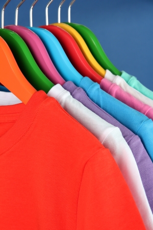 Different shirts on colorful hangers on blue backgroundの写真素材