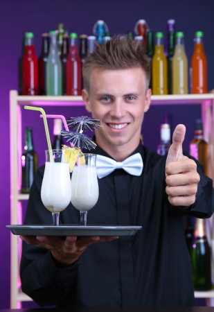 Portrait of handsome barman with Pina colada cocktail, at barの写真素材