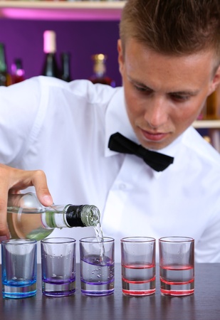 Bartender is pouring  vodka into glassesの写真素材