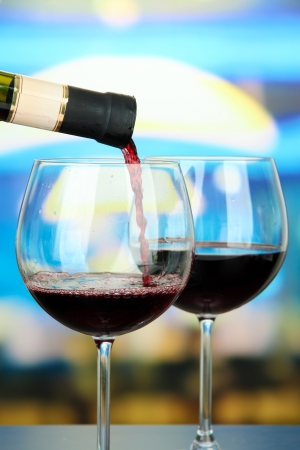 Red wine being poured into wine glass, on bright backgroundの写真素材