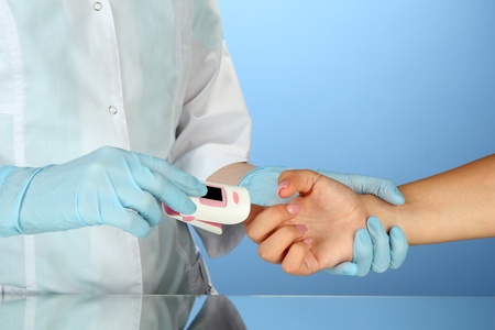 Doctor measuring pulse rate and oxygen levels, on color background