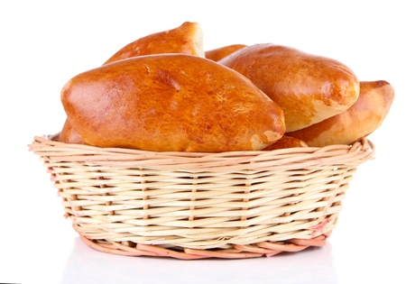 Fresh baked pasties in wicker basket, isolated on whiteの写真素材
