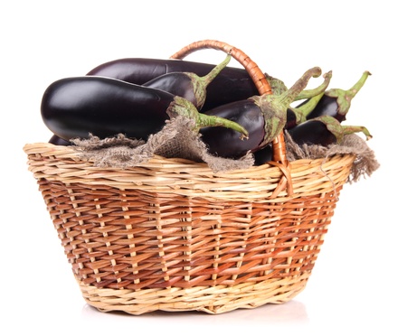 Fresh eggplants in wicker basket isolated on whiteの写真素材