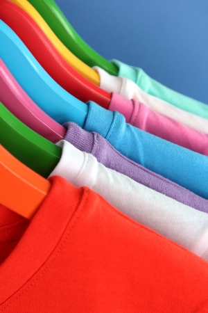 Different shirts on colorful hangers on blue backgroundの写真素材