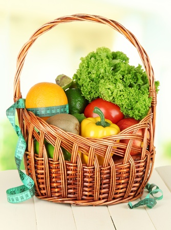 Fresh vegetables in wicker basket on table on light backgroundの写真素材