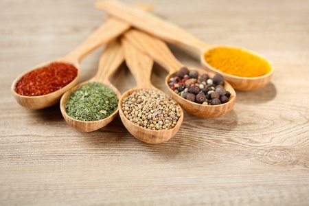 Assortment of spices in wooden spoons on wooden backgroundの写真素材