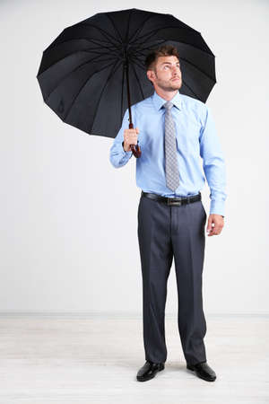 Businessman with umbrella. on gray backgroundの写真素材