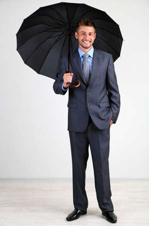 Businessman with umbrella. on gray backgroundの写真素材